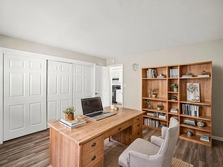 Inviting home office with elegant wooden desk and spacious bookshelves, perfect for productivity and organization.