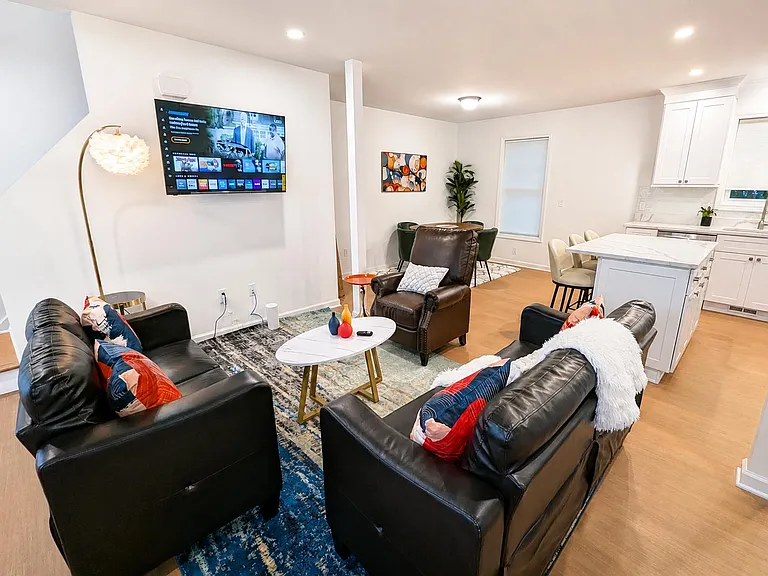 Open-concept living area with comfortable seating, wall-mounted TV, and easy flow to the dining nook and kitchen island.