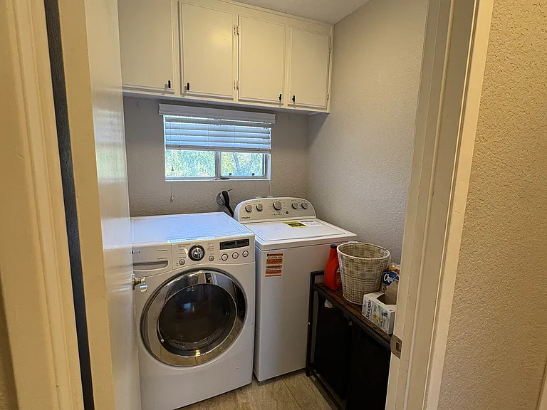 Upstairs Full Size Laundry Room with Gas and Electric Hookups. Storge Cabinets and Tiled Floor