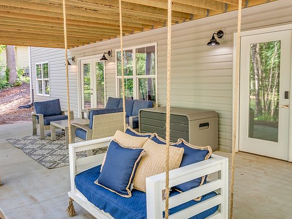 This charming patio offers a relaxing retreat with a traditional Southern swing and additional seating, perfect for morning coffee, quiet conversations, or simply enjoying the fresh air in comfort and style.