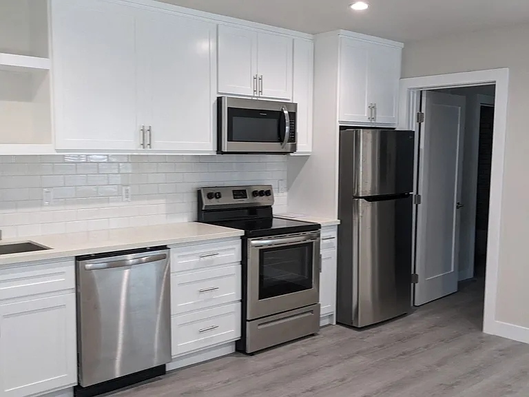 Kitchen with stainless steel appliances and lots of white cabinets at The Hardison Apartments in Pasadena, California.