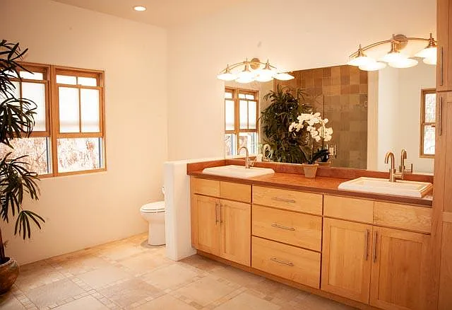 The large shower, soaking tub, double sinks and sandstone counter tops, plus elegant fixtures, gorgeous wood, and tons of storage make this light-filled master bath a relaxing hideaway of its own.