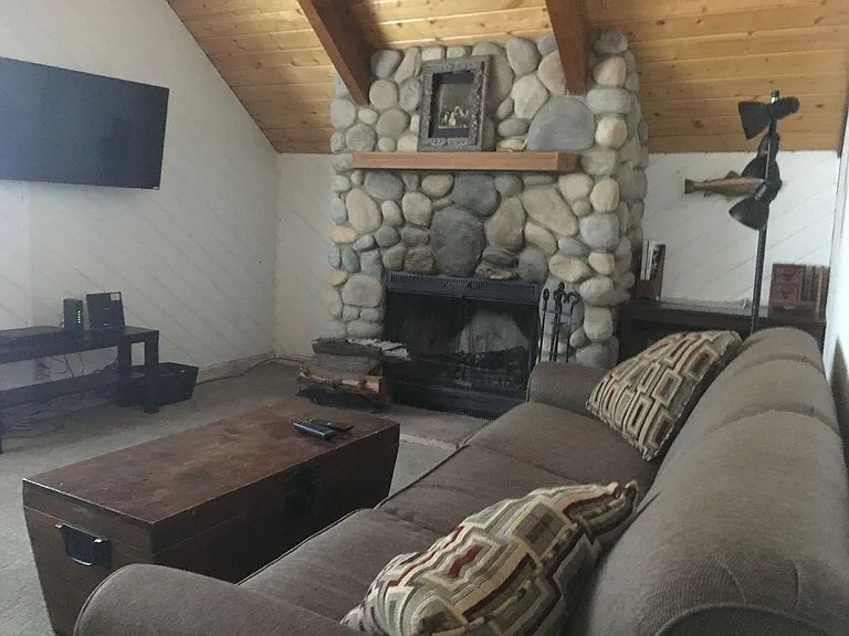 Beautiful wood burning river rock fireplace and sleeper sofa for guests.