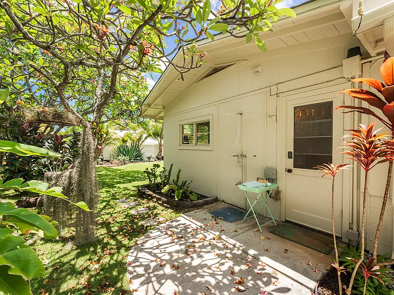 Private outdoor shower area located just off the ensuite bathroom, surrounded by lush tropical landscaping and a mature plumeria tree.