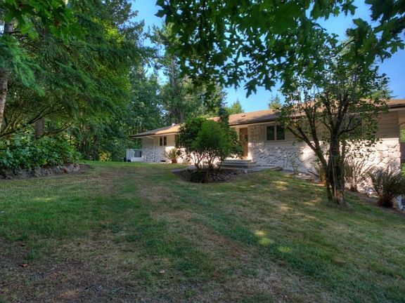 The front of the home, on a fully fenced property. Near level entry provides easy accessibility for all. The roundabout to the left makes for easy parking and driving, as well as leads to the second gate, located on the back side of the property.