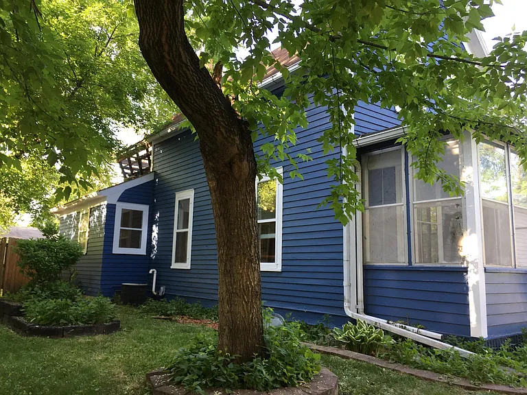 Left side of exterior of the house. Shows screened in porch and gate to backyard.