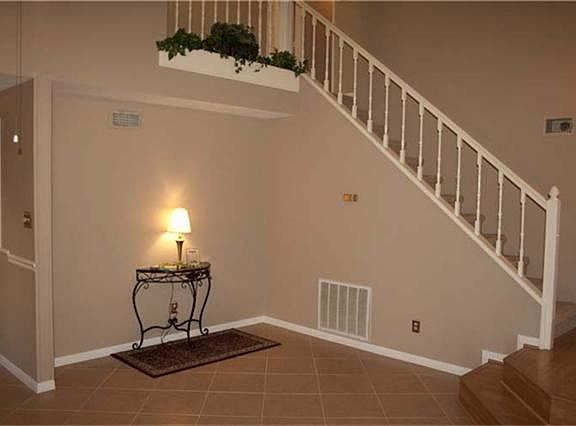Right of living area, white spindle staircase with a ledge for plants at the top.