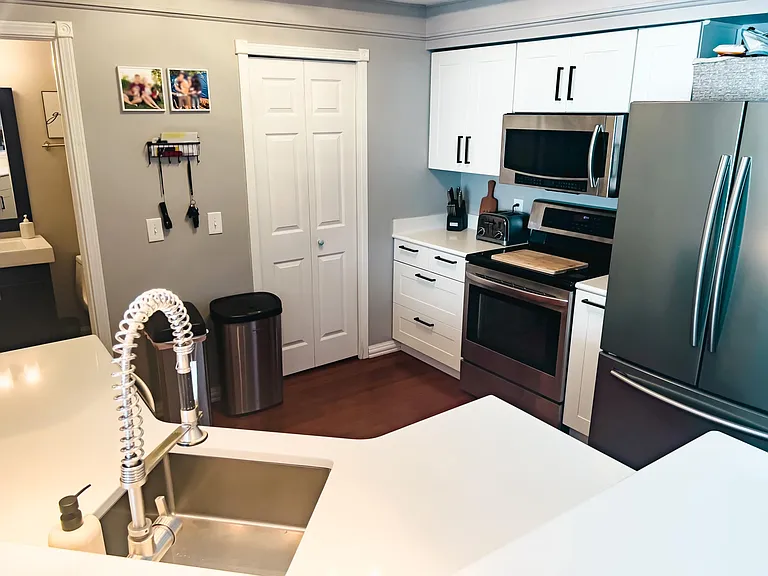 White soft close kitchen cabinets, updated hardware and stainless steel appliances.