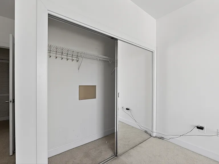 Bedroom closet with mirrored sliding doors and built-in shelf and hanging storage.