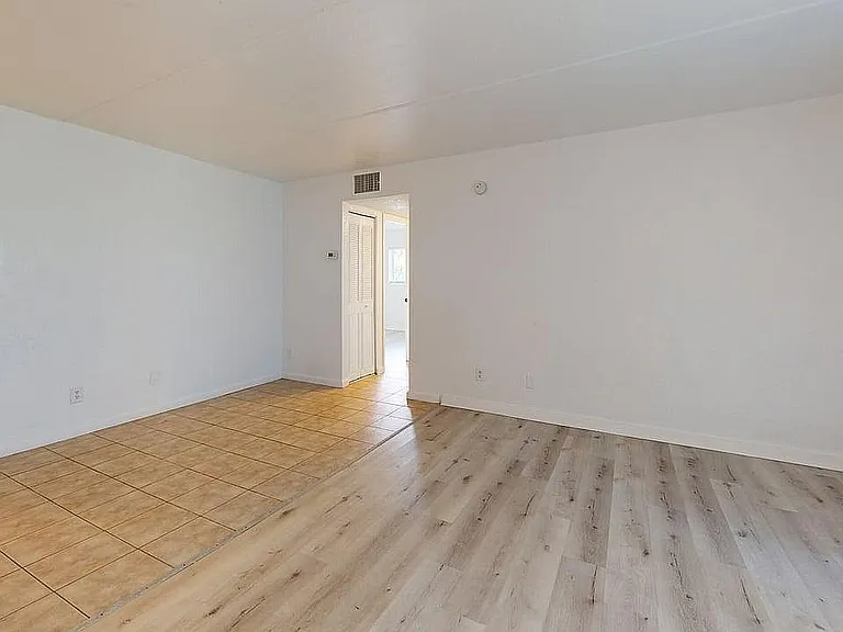 Bright apartment room featuring a mix of elegant tiles and sleek wood flooring with ample natural light.