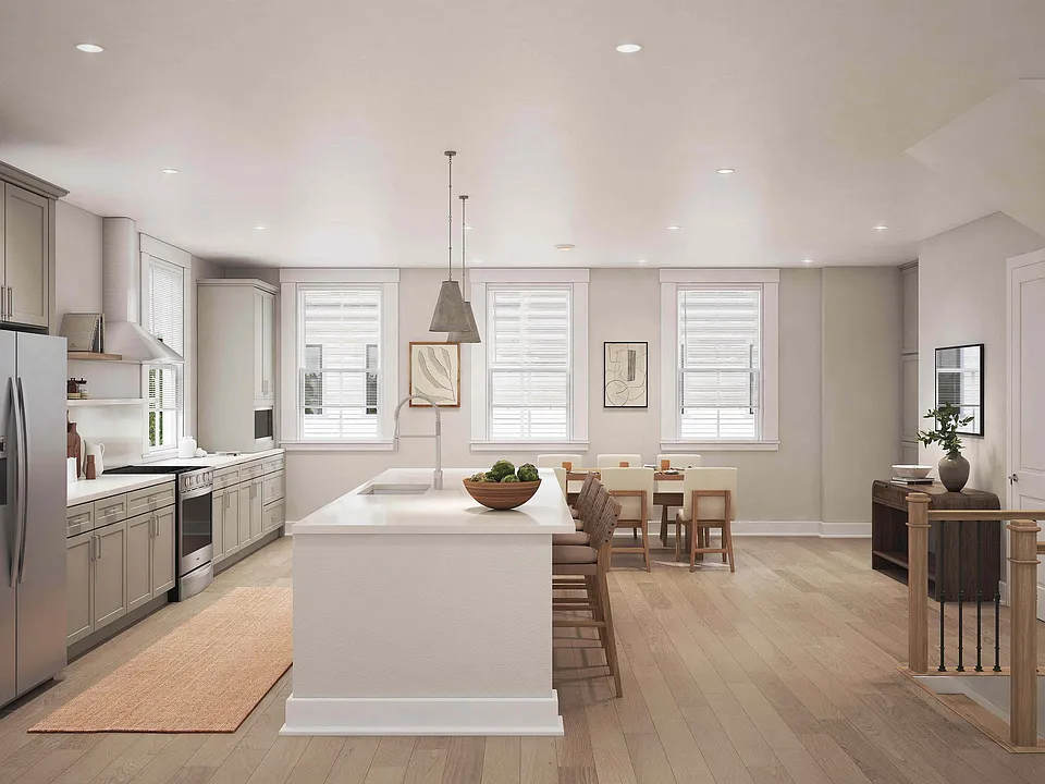 The stylish eat-in kitchen at Fenland Townhomes offers a spacious layout with a large island, high-end finishes, and a dedicated pantry and coffee station for modern living.