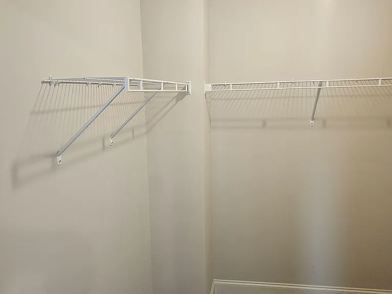 Dedicated walk-in closet with dual wire shelving and hanging space for easy wardrobe and storage organization.