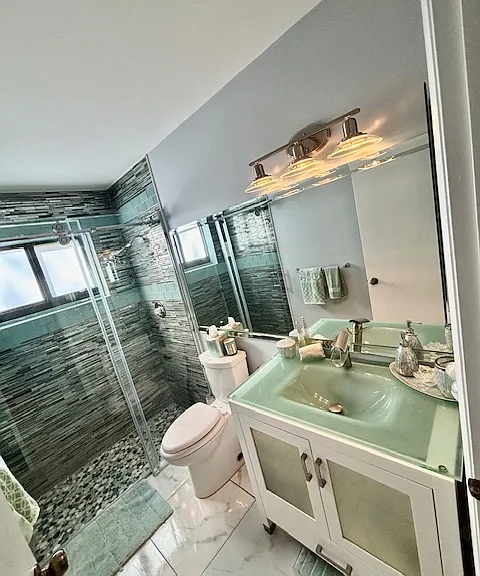 Designer Custom guest Bathroom with green glass sink top, green glass tile walls with stone floor