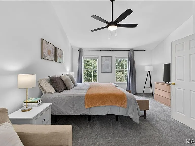 Spacious room featuring vaulted ceilings, a contemporary ceiling fan, and two large windows offering natural light