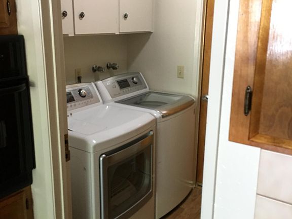 Laundry room adjacent to kitchen and atrium with doors separating all three spaces