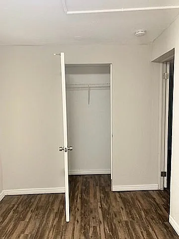 Bright room with sleek hardwood flooring and a spacious closet, perfect for modern living.