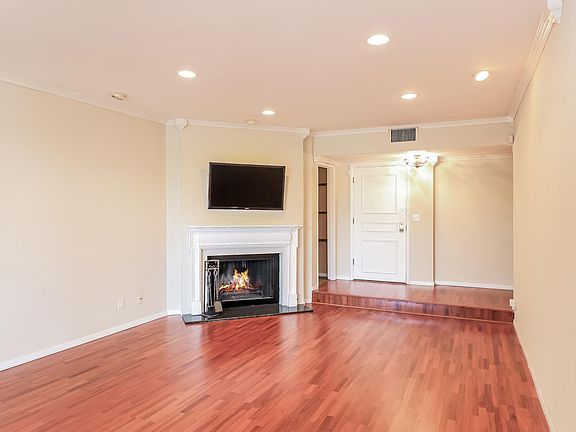 Living Room- Pictured from left to right: Fireplace, wall mounted Flat Screen T.V., doorway leading to Custom Kitchen, front door that leads to the main hallway.
