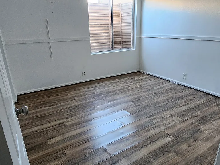 Spacious lower-level bedroom featuring updated flooring, natural light, and a versatile layout ideal for a guest room, office, or private retreat.