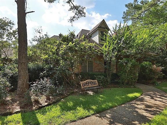 The front walk leads to a large front porch and main entry. There are many beautiful plants and shrubs all around the home.