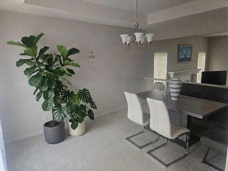 Dining area with a long table, seating, and chandelier lighting, and an open layout that flows to nearby living space.