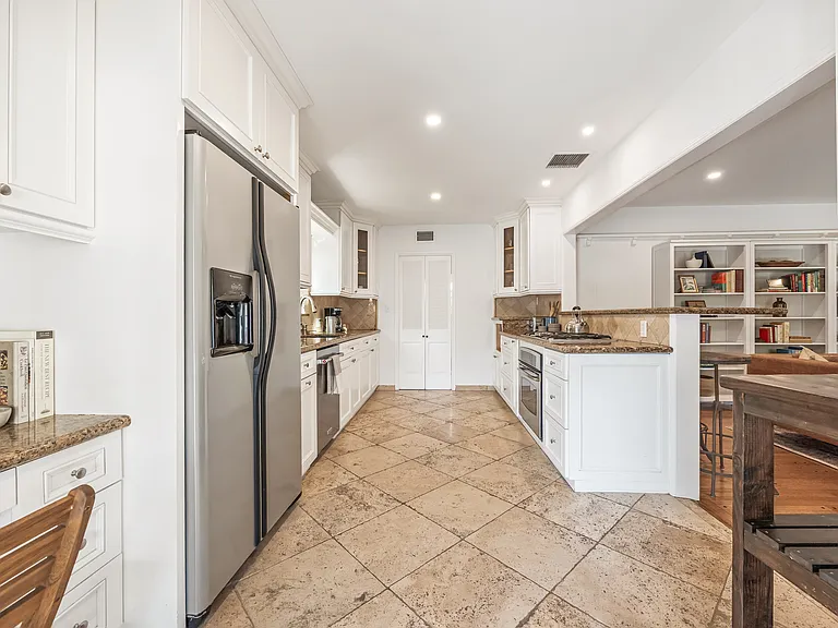 Fully stocked kitchen with abundant natural light, backyard views, bar seating, and a convenient work station for everyday living.