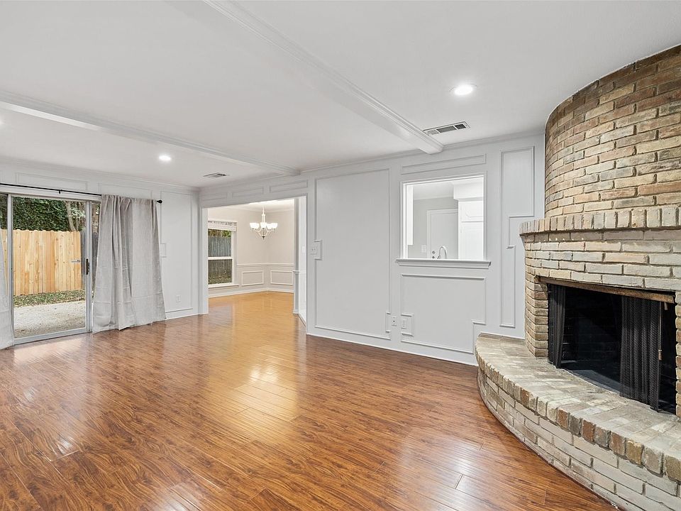 Living room with wood burning fireplace and sliding glass doors that lead out to fenced in side yard and patio.