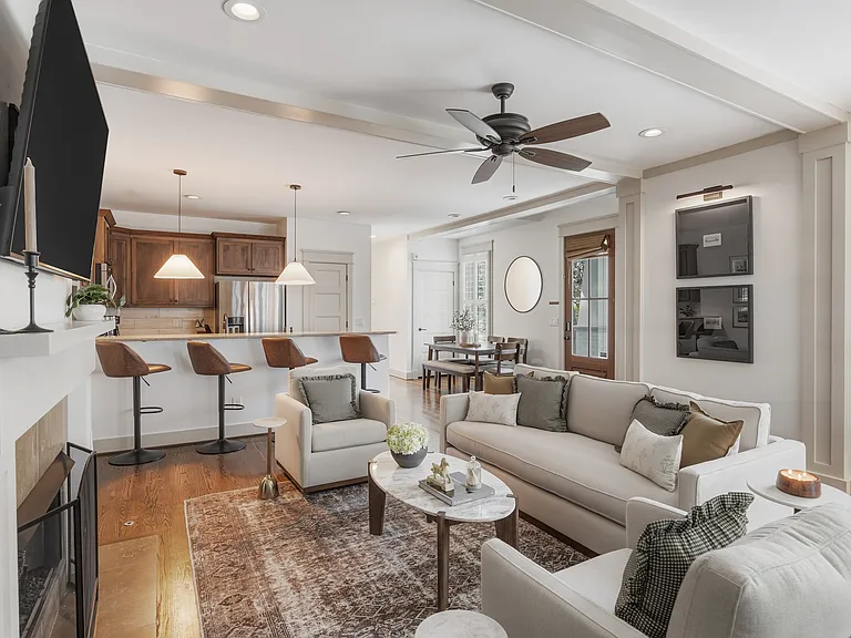 Beautifully designed living room with a fireplace, ceiling fan and plenty of comfy seating. Smart TV, wood floors, and easy flow into the kitchen.