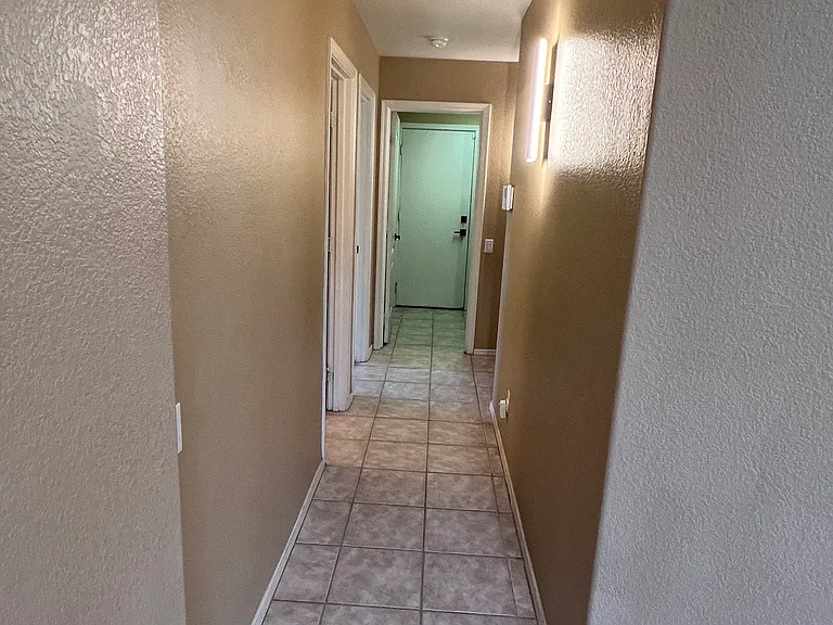 downstairs hallway leaving family room going toward full hallway bathroom, bedroom, laundry room, and front door