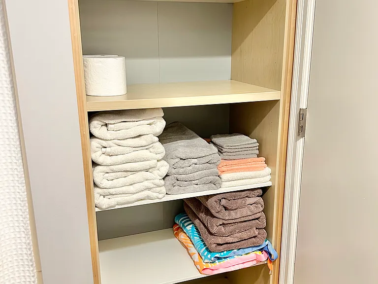 Lower level bathroom storage shelves stocked with towels.