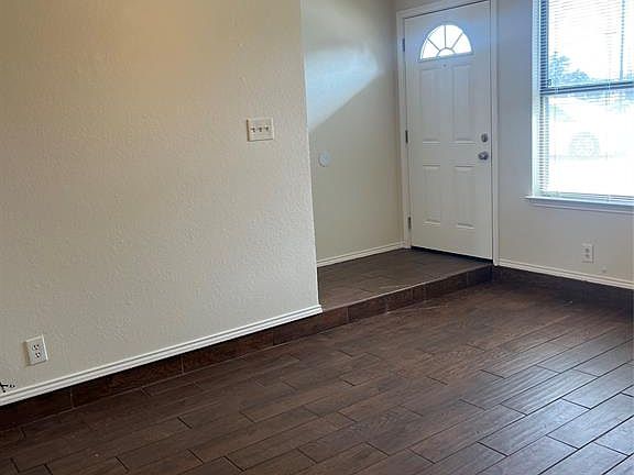 Foyer entrance with a textured ceiling, dark wood-style flooring, and ceiling fan