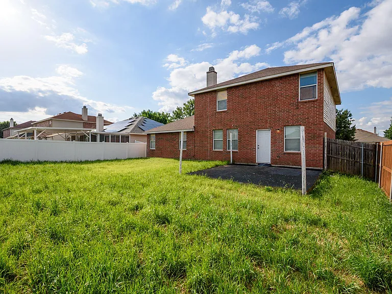 Fenced backyard with a grassy lawn and rear entry, offering space for outdoor relaxing and everyday convenience.