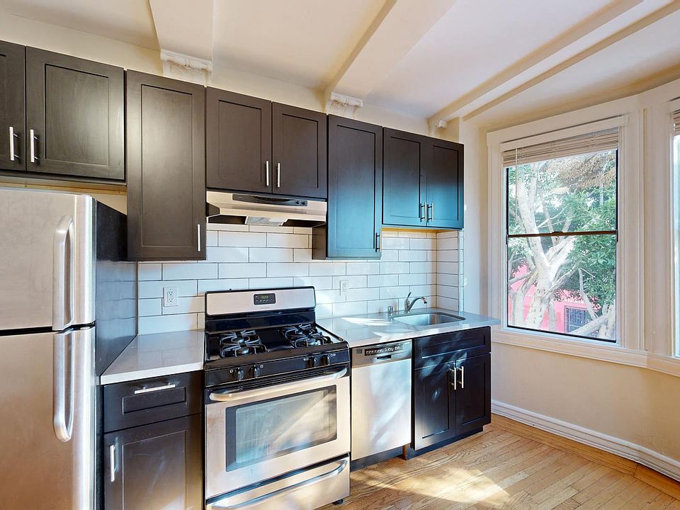 Kitchen with multiple cabinets, refrigerator, stove, range hood, and sink