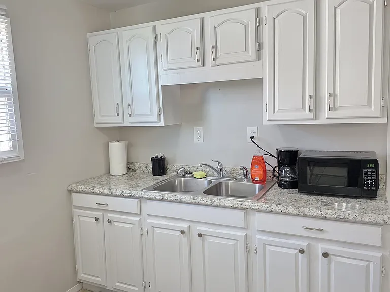Kitchen workspace with ample white cabinetry, double-basin sink, and generous counters for meal prep and storage.
