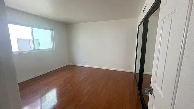 View from hallway into guest bedroom. Large closet and window (view to next door complex).
