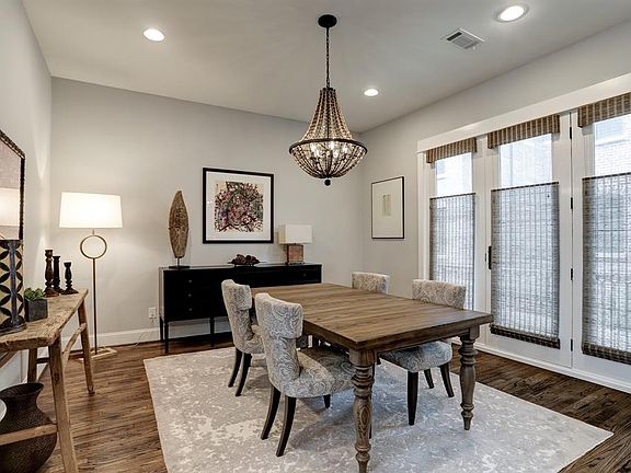 Spacious, light-filled dining room has a contemporary decorative chandelier and French doors leading to a balcony with gas outlet.