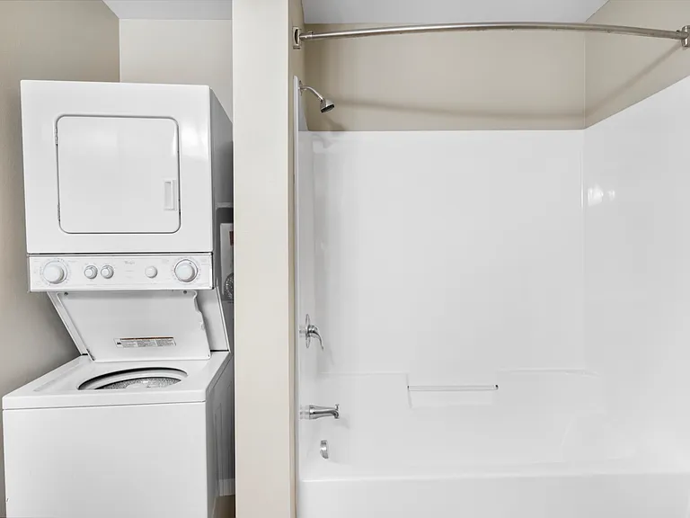 Modern bathroom with a convenient in-unit washer and dryer combo, next to a pristine white bathtub. Modern bathroom with a convenient in-unit washer and dryer combo, next to a pristine white bathtub.
