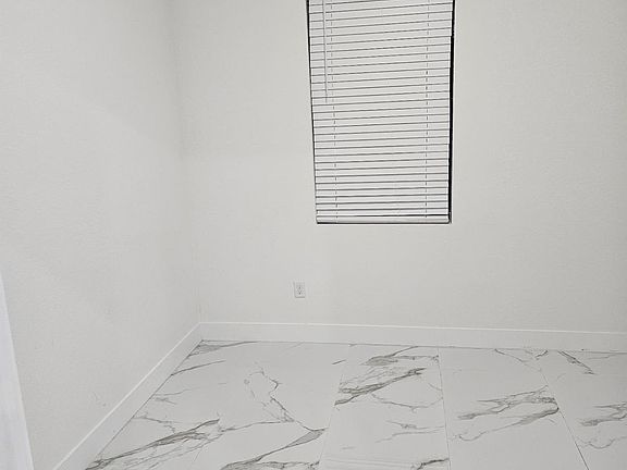Bright Bedroom with Large Window, Modern Marble-Look Tile Flooring, and Clean Neutral Finishes
