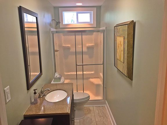 Tile and granite bathroom with natural lighting above the sh