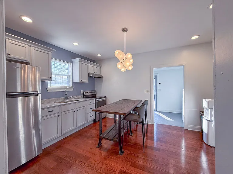 Large eat-in kitchen with stainless steel fridge, electric stove and hood, and rustic counter height table. Cookware and kitchen tools included, including an air fryer.