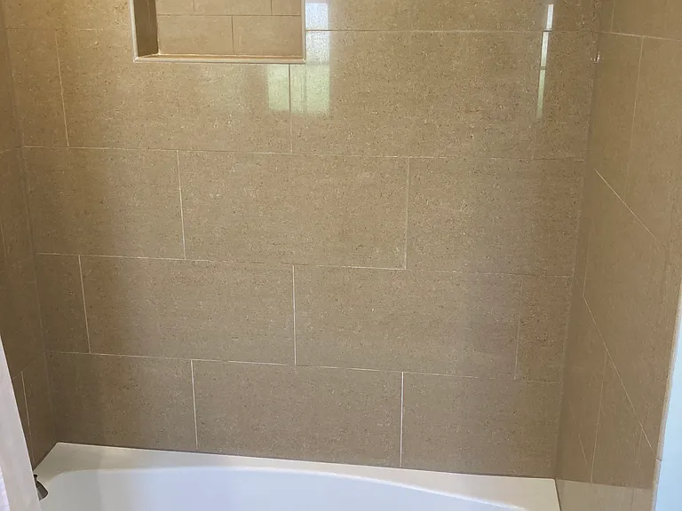 Oversized, tiled bath tub/shower combo with storage caddy
