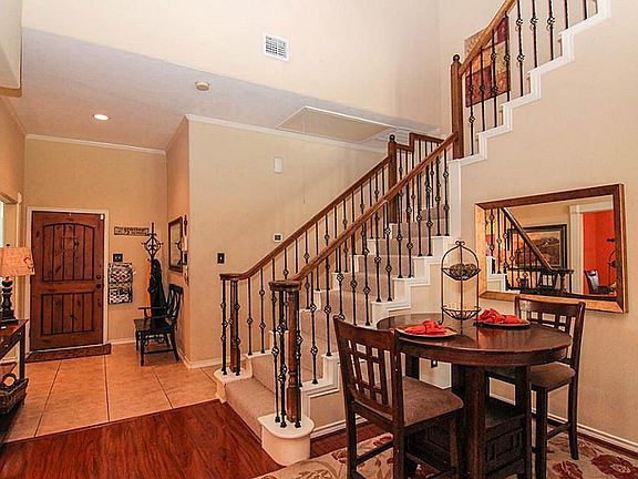 The entry features tiled floors and an elegant staircase with wrought iron spindles.