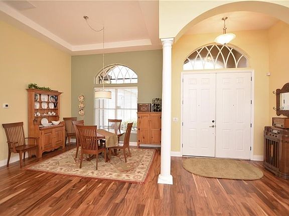 Double door entry to grand foyer with sophisticated architectural appeal and gleaming wood floors.