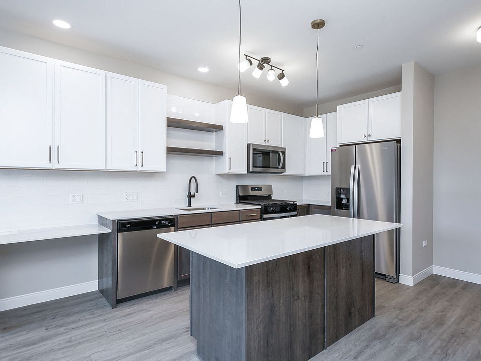 Kitchen with stainless steel whirlpool appliances, quartz countertops, floating shelves and two tone cabinets