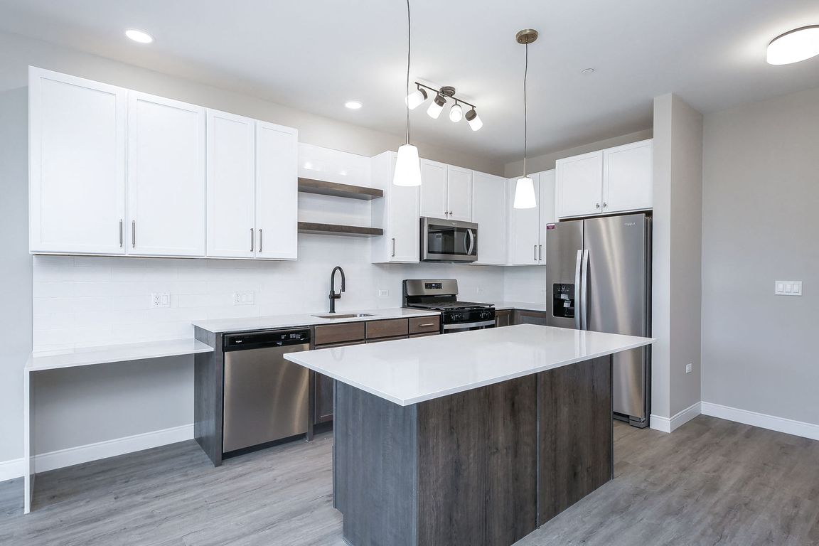 Kitchen with stainless steel whirlpool appliances, quartz countertops, floating shelves and two tone cabinets