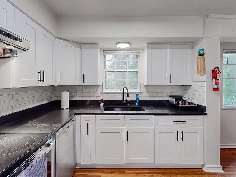 Kitchen features shaker cabinets, subway-tile backsplash, generous counters, and a window over the sink for daily prep.