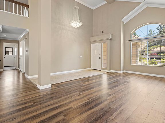 Open sitting and dining area with high ceilings and chandelier.