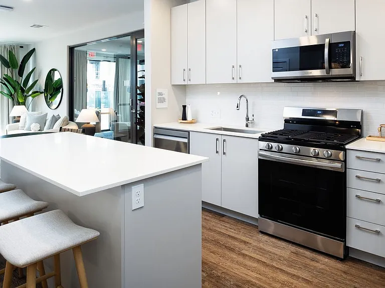 Showroom kitchen with stainless steel appliances, white quartz countertop, light grey cabinetry, and hard surface flooring