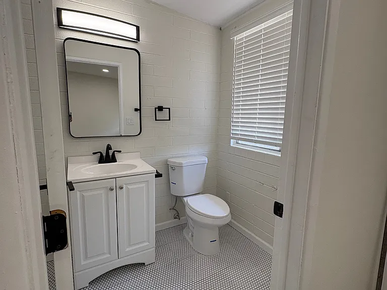 Bathroom with shower / tub combo, new penny tile and subway tile, toilet and vanity.
