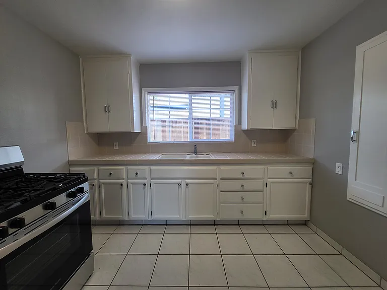 Kitchen with new fridge and gas range. New lighting. Cabinets painted with new hardware. Easy to clean tile flooring.