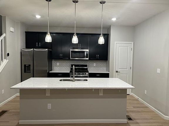 Stain steel appliances and quartz counters, pendant lights and shaker style cabinets with soft close and crown molding. Herringbone pattern backsplash. Refrigerator with icemaker and water dispenser.